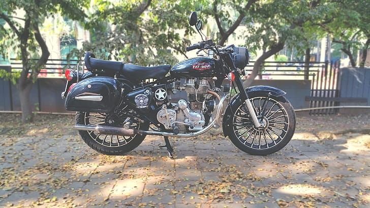 Black Royal Enfield motorcycle parked under trees before shipping from Delhi to Cuttack