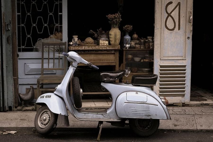 Vintage white scooter parked outside a shop, an example of scooters shipped from Delhi to Bangalore
